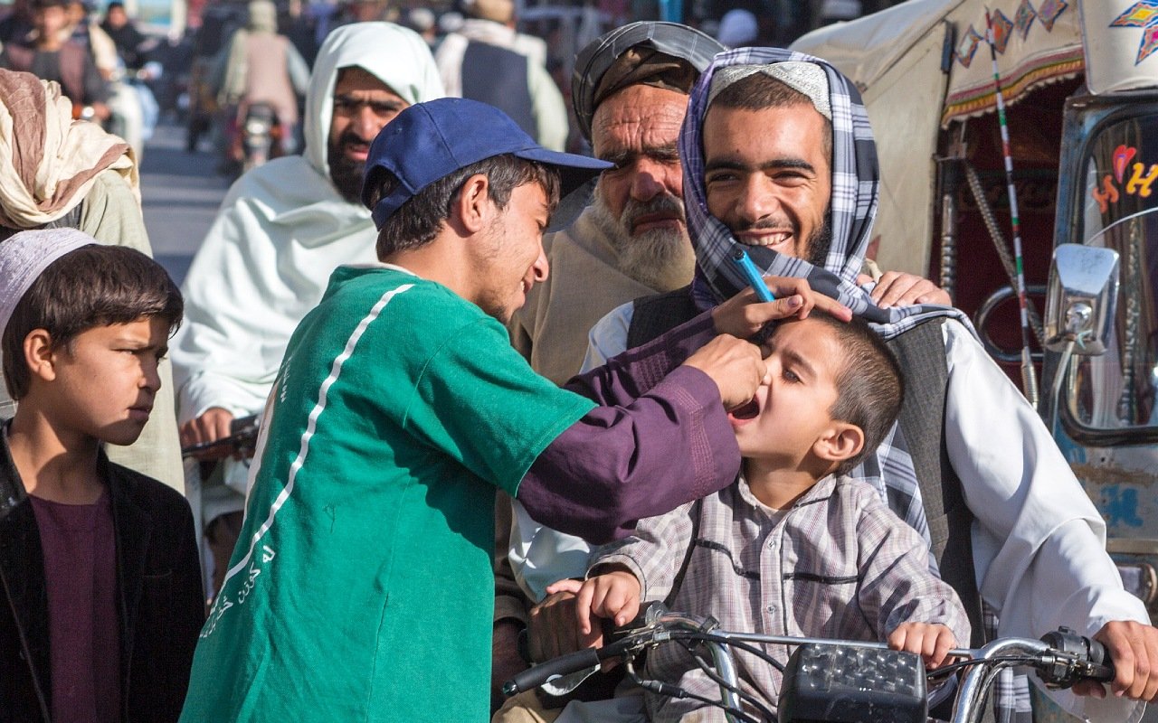 Contractual arrangements thumb Volunteer vaccinating a Afghan boy against Polio on a busy street.