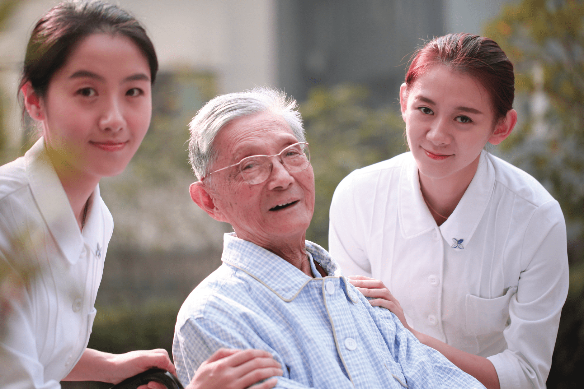 Stigma-min Two care professionals supporting an older man in a wheelchair explore a garden.