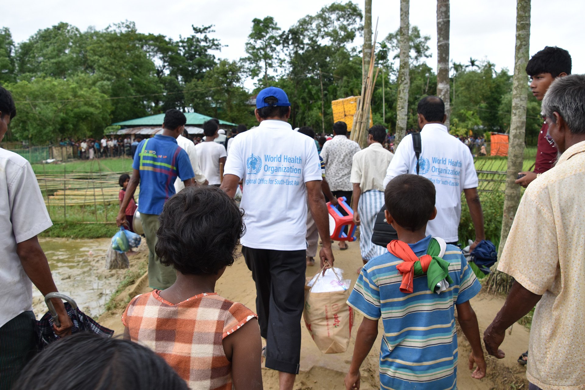 responding-coxs-bazar a group of people including some children walking with their backs to the camera